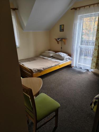 a bedroom with a bed and a chair and a window at U TKOCZA Agroturystyka in Wisła