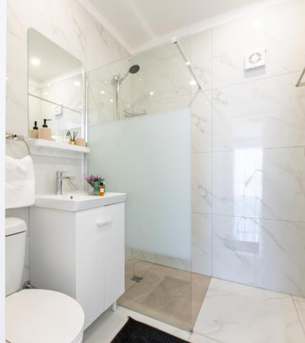 a white bathroom with a shower and a toilet at TelMar Sea View - 2 min walk to the Beach in Oroklini
