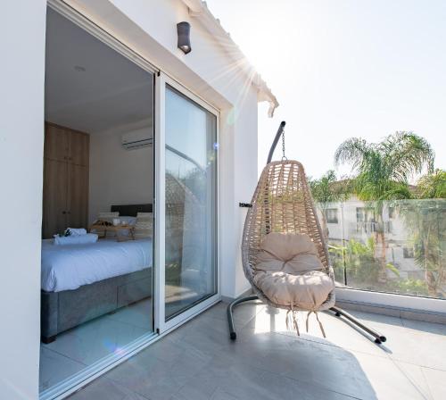 une chaise en rotin dans une pièce avec une chambre dans l'établissement TelMar SeaView, à Oroklini