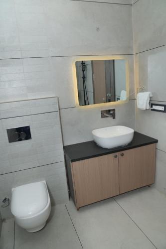 ein Badezimmer mit Waschbecken, Toilette und Spiegel in der Unterkunft Den Inn in Hisār