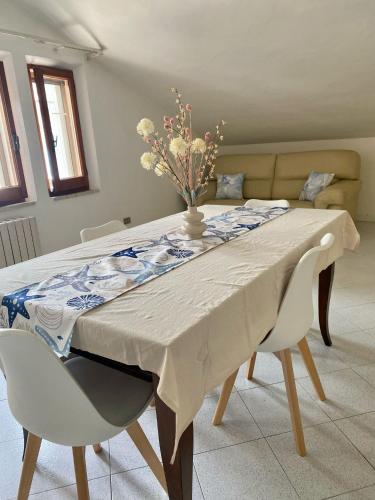 een eettafel met een vaas met bloemen erop bij Casa Roberto in Giulianova