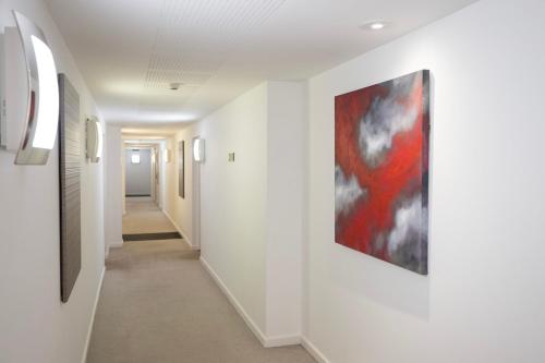 einen Flur mit weißen Wänden und einem Gemälde an der Wand in der Unterkunft Modern 1BR Apt - Sleeps 4 - Parking - Balcony in Hoo