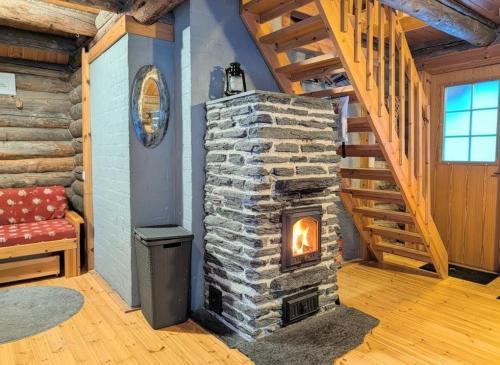 a stone fireplace in a room with a staircase at Villa Kelotupa in Hossa