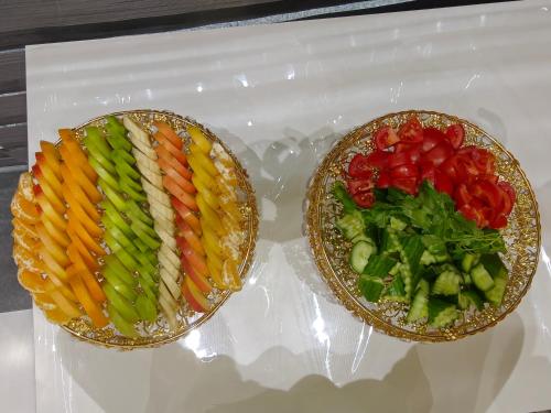 Dos platos de comida con verduras en una bandeja de plástico. en Diyor Hotel & Spa Tashkent, en Tashkent