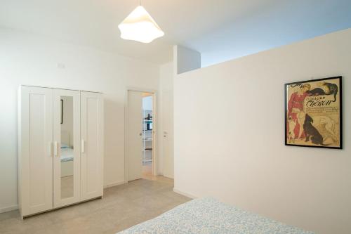 a bedroom with white walls and a painting on the wall at MagliaNeraApartment in Quartu Sant'Elena