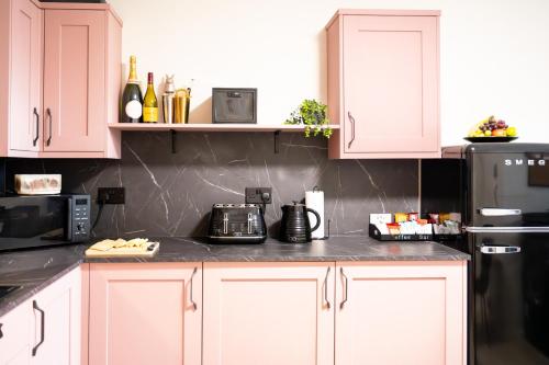 a kitchen with white cabinets and a black refrigerator at Northern Hideaways, The Nest Ponteland in Newcastle upon Tyne