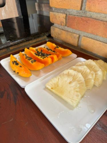 een wit bord met fruit en kaas op een tafel bij Pousada Vila Coral in Ubatuba
