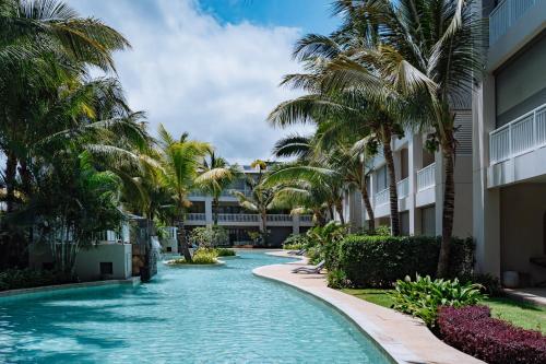ein Swimmingpool mit Palmen vor einem Gebäude in der Unterkunft Apartment in a Tropical Oasis, Ki Residences, Pereybere - Managed by KSN in Pereybere
