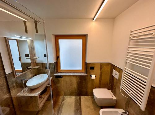 a bathroom with a sink and a toilet and a window at Cesa Bernard - Apartment Cima 12 e new Apartment Fraine in Pozza di Fassa