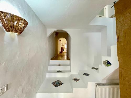 un couloir avec des murs blancs et des escaliers avec un lustre dans l'établissement Sidi Bou Said for two, à Dar el Ouzir