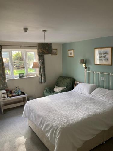 a bedroom with a bed and a chair and windows at Brandreth Barn in Burscough