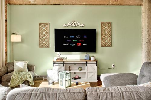 a living room with a couch and a tv on a wall at The Magnolia - Farmhouse Loft - Sleeps 10 - Valet in Dallas