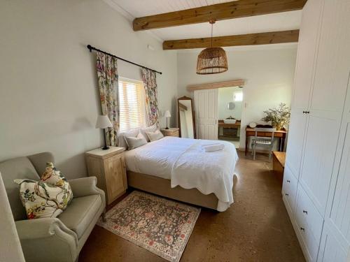 a bedroom with a bed and a chair and a desk at Jonkershuis Farm Retreat in Heidelberg