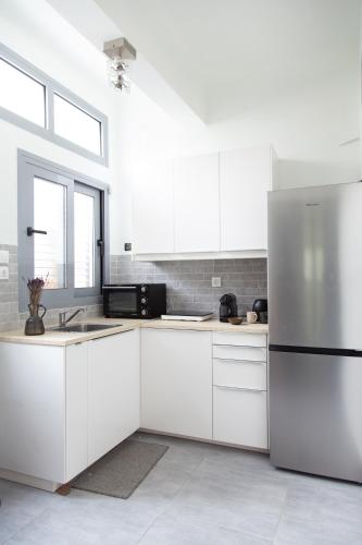 a kitchen with white cabinets and a stainless steel refrigerator at Central Urban Retreat in Athens