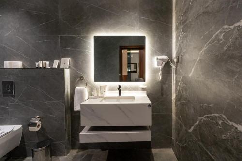 a bathroom with a white sink and a mirror at Jovan suites apartment in AlUla