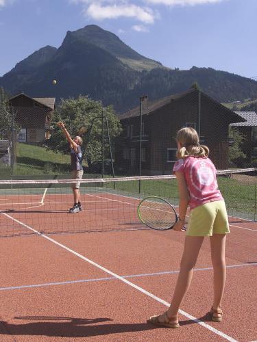 two young girls playing tennis on a tennis court at Hôtel Les Côtes, Résidence Loisirs et Chalets in Morzine
