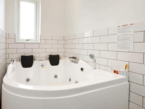 a white tub in a white bathroom with a window at Exclusive Golf View Retreat in Rømø Kirkeby