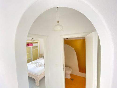 une voûte menant à une salle de bains avec lavabo dans l'établissement Deluxe Apartment - Vlichada Beach, à Santorini