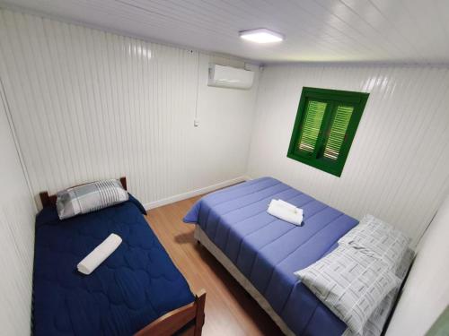1 dormitorio con 2 camas y una ventana verde en Casa Sander Gramado, en Gramado