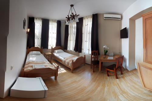 a living room with two beds and a table at Pensiunea Muresul in Târgu-Mureş