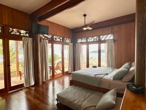 a bedroom with two beds in a room with windows at Bocas Beachfront Lodge Spacious Corner King Suite Ocean View Sand Level in Bocas del Toro