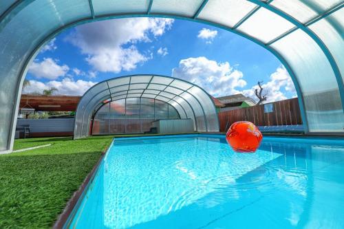 a swimming pool with an archway and an orange ball at אגם בגליל -וילה ו-3 סוויטות מקסימות למשפחות עם בריכה מחוממת in Wadi Keren