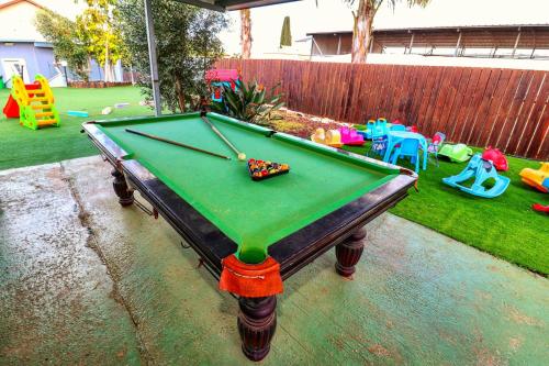 a pool table in a backyard with a play area at אגם בגליל - וילה ו-3 סוויטות עם בריכה מחוממת בעבדון in Wadi Keren