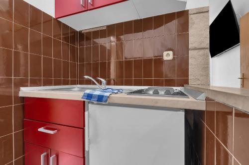 a kitchen with a sink and red cabinets at Apartments Harmony of Five in Makarska