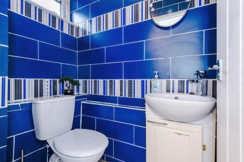 a blue tiled bathroom with a toilet and a sink at Middleton 4 Bed Free Parking Long stays in Middleton