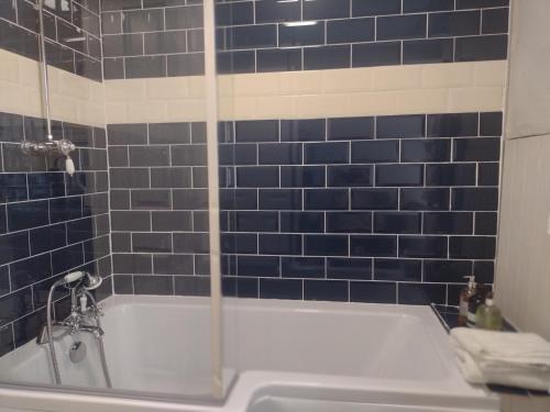 a blue tiled bathroom with a white tub and blue tiles at 2 Courtyard Mews in Penzance