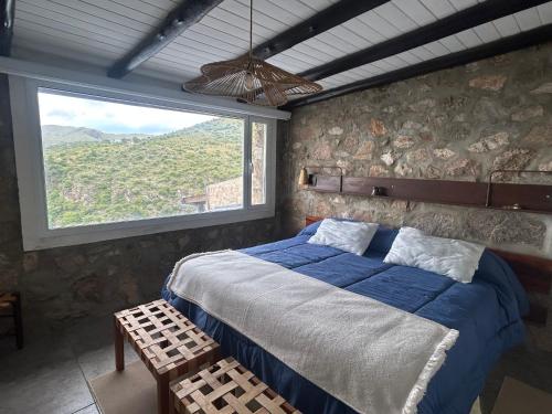 a bedroom with a bed and a large window at suites en la montaña con propuesta de viñedo in La Cumbre