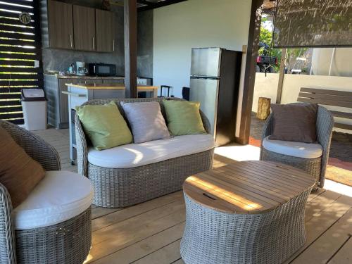 a patio with wicker chairs and a couch and a table at Doa Blanca Cabin Mountain View in Utuado
