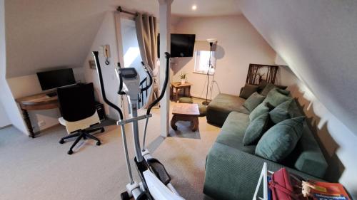 a living room with a green couch and a desk at Hébergement 4 personnes proche centre ville Strasbourg in Strasbourg