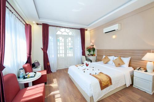 a bedroom with a large white bed and red chairs at Palm Beach Hotel in Nha Trang