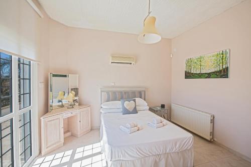 a white bedroom with two beds and a mirror at Papas Family Villa in Paralimni