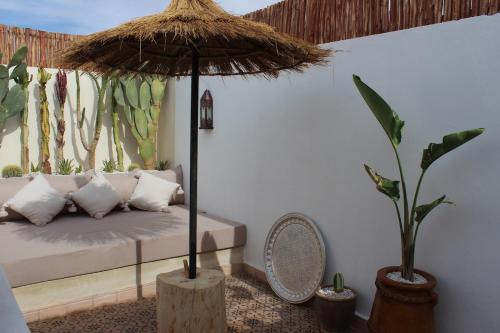 a room with a bed and a umbrella and plants at Riad de charme privatisé au cœur de la médina in Oulad Akkou