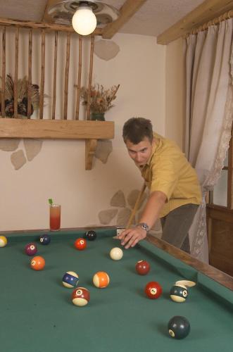 a man playing pool with a cue on a pool table at Hôtel Les Côtes, Résidence Loisirs et Chalets in Morzine