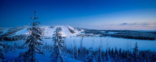 Una escena invernal de un pueblo en una montaña nevada en Ukkohalla Chalets, en Hyrynsalmi