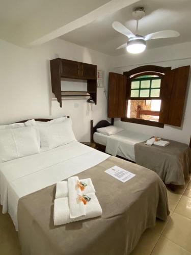 a hotel room with two beds and a window at Pousada Marendaz in Paraty
