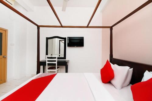 ein Schlafzimmer mit einem Bett mit roten Kissen und einem Spiegel in der Unterkunft Royal Oshin Hotel in Wadduwa