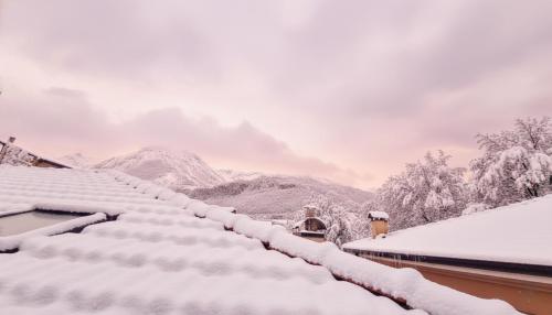 a snow covered roof of a house with mountains in the background at a 200m dai mercatini TERRAZZO PANORAMICO LOFT in Centro Storico-Stazione in Trento