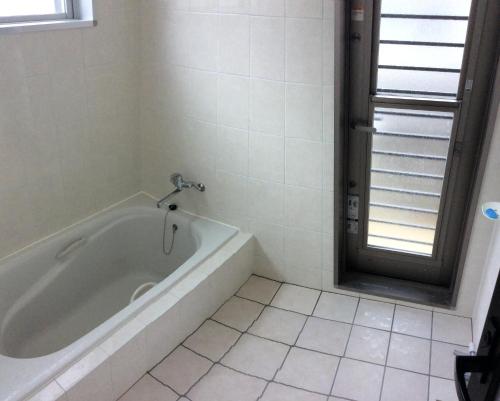 a white bath tub in a bathroom with a window at Seaside House Nirai in Miyako Island