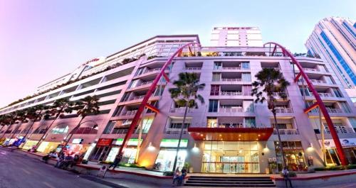 a large white building with palm trees in front of it at Modern Suite near BTS Nana Netflix Sky View in Makkasan