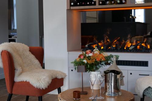 a living room with a fireplace and a table with flowers at Garrigae Caserne de Briançon & SPA Cinq Mondes in Briançon