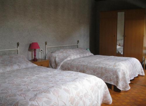 1 Schlafzimmer mit 2 Betten mit weißer Bettwäsche und einer Lampe in der Unterkunft Maison Usclade Murat-le-Quaire in La Celle-sous-Gouzon