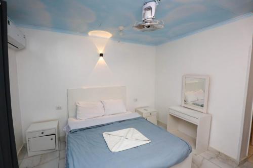 Dieses weiße Zimmer verfügt über ein Bett mit einer blauen Decke. in der Unterkunft Luxor Nile Palace in Luxor