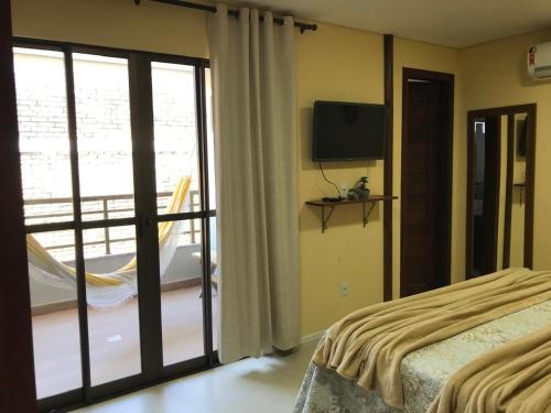 Un dormitorio con una cama y un balcón con televisión. en AP 205 - Flecheiras Residence, en Flecheiras