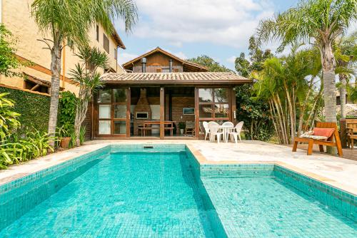 eine Villa mit einem Swimmingpool vor einem Haus in der Unterkunft Recanto das Palmeiras in Guarda do Embaú