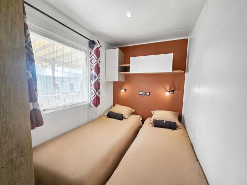 two beds in a small room with a window at L'horizon du bonheur in Litteau