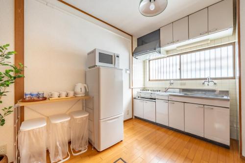 a kitchen with a white refrigerator and a sink at GUEST HOUSE Hotori 2nd in Otsu